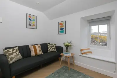 a living room with a black couch and a window at White Mist Cottage in St Ives