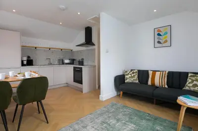 a kitchen and a living room with a couch and a table at White Mist Cottage in St Ives