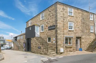 an old stone building with stairs on a street at White Mist Cottage in St Ives