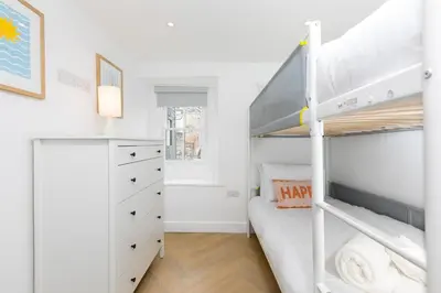 a bedroom with a bunk bed and a desk at White Mist Cottage in St Ives