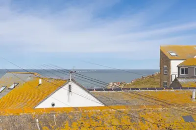 a view of roofs of houses and the ocean at White Mist Cottage in St Ives