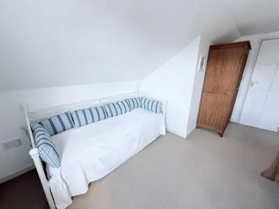 a bedroom with a white bed and a wooden door at Meadow View - Widemouth Bay Cornwall in Widemouth Bay