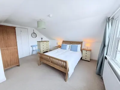a bedroom with a large bed and a window at Meadow View - Widemouth Bay Cornwall in Widemouth Bay