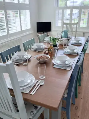 a wooden table with plates and bowls of food on it at Meadow View - Widemouth Bay Cornwall in Widemouth Bay