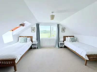 two beds in a room with a window at Meadow View - Widemouth Bay Cornwall in Widemouth Bay