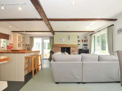 a living room with two couches and a kitchen at Upper Court Cottage in Bude