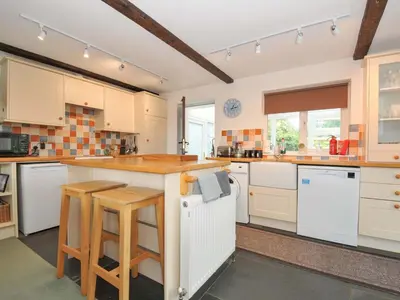 a large kitchen with white cabinets and a counter at Upper Court Cottage in Bude