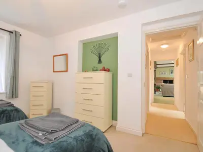 a bedroom with a bed and a dresser and a bathroom at Upper Court Cottage in Bude