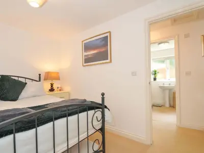 a bedroom with a bed and a bathroom at Upper Court Cottage in Bude