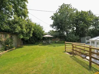 a yard with a wooden fence and a garden at Upper Court Cottage in Bude