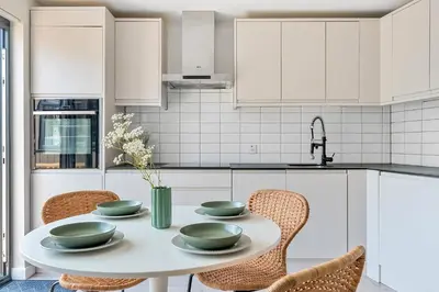 a white kitchen with a table and chairs at Palm House in Newquay