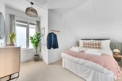 a white bedroom with a bed and a window at Palm House in Newquay