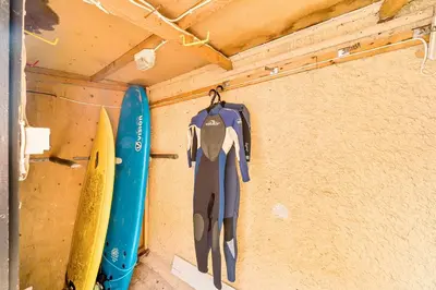 a room with a surfboard and a wetsuit hanging on a wall at Palm House in Newquay