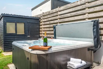 a hot tub with a bottle of wine and a glass at Palm House in Newquay