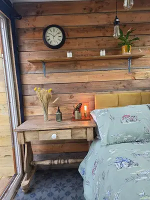 a bedroom with a wooden wall with a clock and a bed at Miss Francis Horse Wagon in Looe