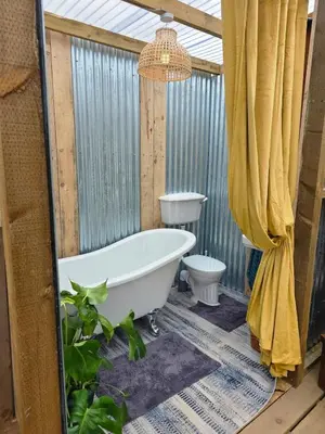 a bathroom with a tub and a toilet at Miss Francis Horse Wagon in Looe