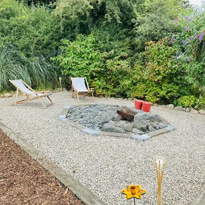 two chairs and a fire pit in a yard at Harpers Huts in Lanivet