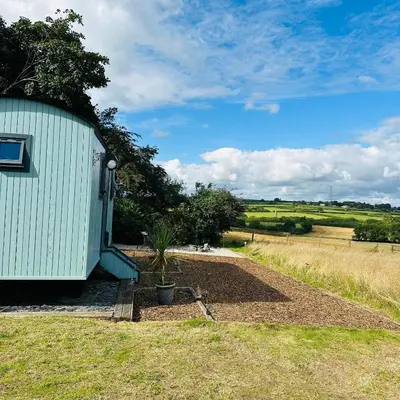 a garden next to a building with a plant at Harpers Huts in Lanivet