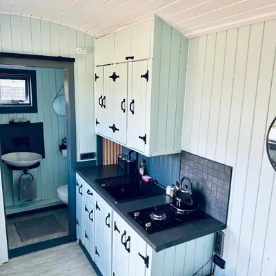 a kitchen with blue and white cabinets and a sink at Harpers Huts in Lanivet