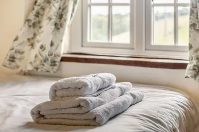 a pile of towels sitting on a bed in front of a window at 2 Bed in Liskeard oc-t32876 in Duloe