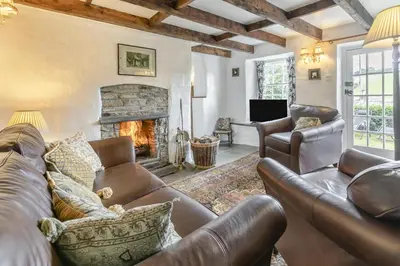 a living room with leather furniture and a fireplace at 2 Bed in Liskeard oc-t32876 in Duloe