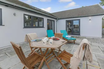 a patio with a wooden table and chairs at 4 Bed in Padstow oc-r32776 in Padstow