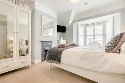 a white bedroom with a large bed and a fireplace at 3 Bed in Padstow oc-g32860 in Padstow