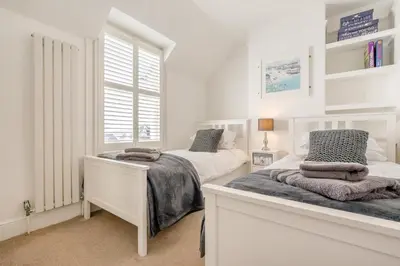 a white bedroom with two beds and a window at 3 Bed in Padstow oc-g32860 in Padstow