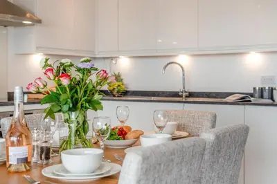 a kitchen with a table with flowers and wine glasses at 3 Bed in Tintagel oc-e32938 in Tintagel