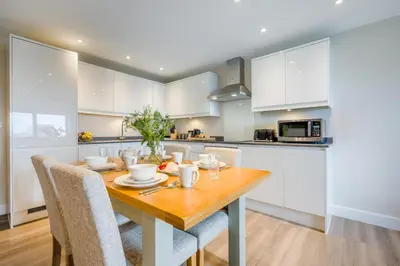 a kitchen with white cabinets and a wooden table with chairs at 2 Bed in Tintagel oc-a32939 in Tintagel
