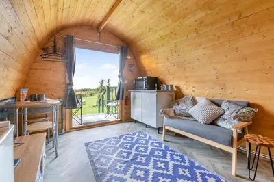 a living room with a couch and a kitchen with a window at 1 Bed in Four Lanes oc-s32768 in Carnbrea