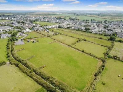 an aerial view of a village with a green field at 1 Bed in Four Lanes oc-b32769 in Carnbrea