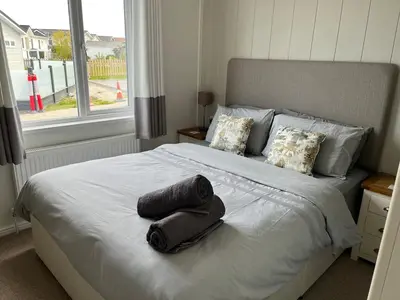 a bedroom with a large white bed with a window at Lodge in St Merryn in St Merryn