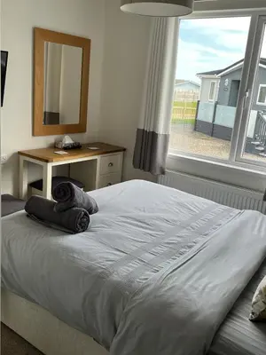 a bedroom with a bed with a mirror and a window at Lodge in St Merryn in St Merryn