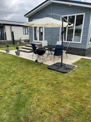 a patio with a grill and chairs and an umbrella at Lodge in St Merryn in St Merryn