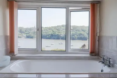 a bath tub in a bathroom with a window at Kiln Cottage in Fowey