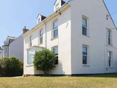 a white house with a tree in front of it at Tregundy Farmhouse in Perranporth