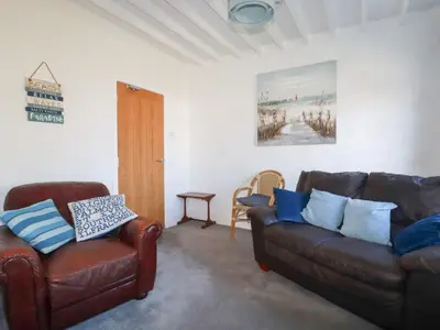 a living room with two leather couches and a table at Tregundy Farmhouse in Perranporth