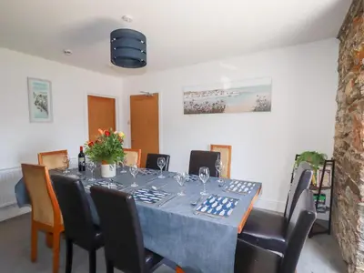 a dining room with a long table and chairs at Tregundy Farmhouse in Perranporth
