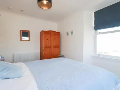 a bedroom with a white bed and a window at Tregundy Farmhouse in Perranporth