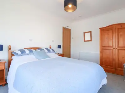 a bedroom with a large white bed and a wooden cabinet at Tregundy Farmhouse in Perranporth