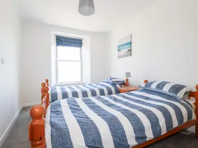two twin beds in a bedroom with a window at Tregundy Farmhouse in Perranporth