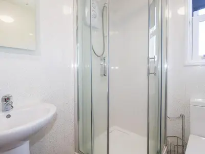 a bathroom with a glass shower and a sink at Tregundy Farmhouse in Perranporth