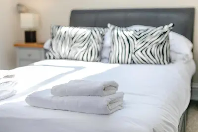 a pile of towels sitting on a white bed at 3 Bed in Newquay oc-o32259 in Newquay