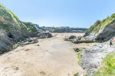a beach with people laying on the sand and cliffs at 3 Bed in Newquay oc-o32259 in Newquay