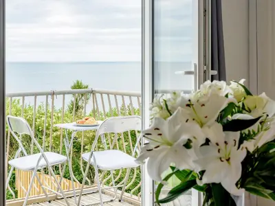 a balcony with a table and chairs and flowers at On The Beach in Downderry
