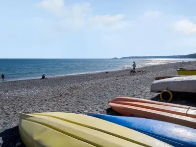 a group of kayaks on a beach with the ocean at On The Beach in Downderry