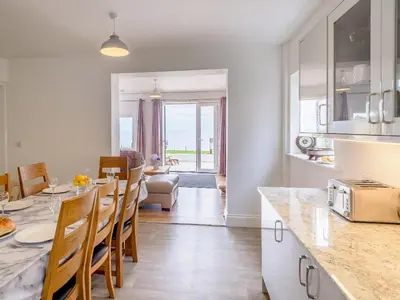 a kitchen and dining room with a table and chairs at On The Beach in Downderry