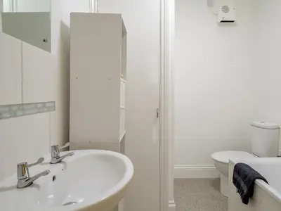 a white bathroom with a sink and a toilet at On The Beach in Downderry