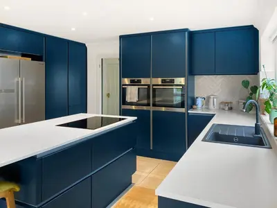 a kitchen with blue cabinets and a white counter top at Kerensa in St. Agnes